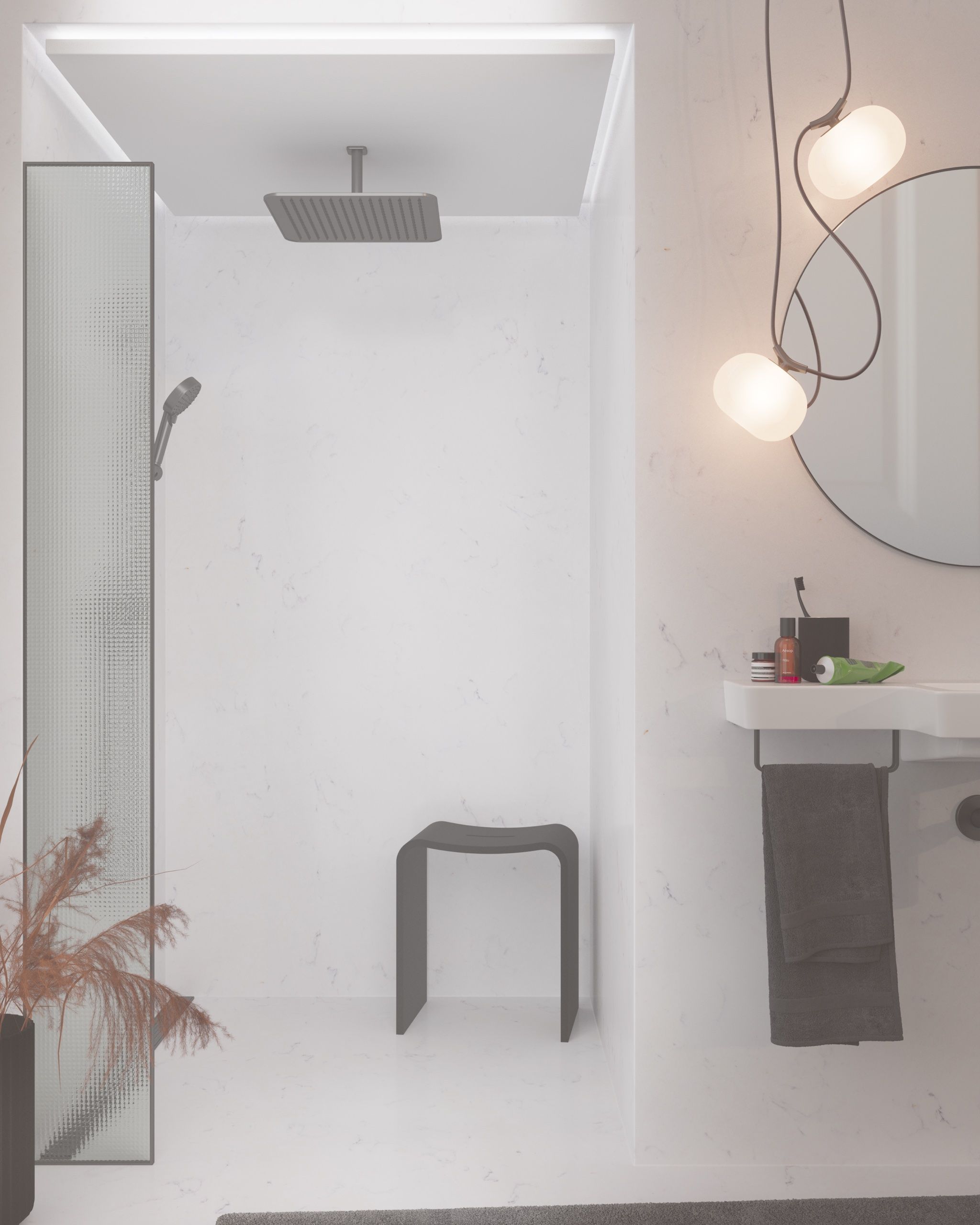 A render of a narrow bathroom lined in pale veined stone: a walk in shower with a square ceiling rain head, a hand shower and a dark grey stool, a fluted glass screen and a dried grass arrangement at the left, and on the right a wall hung basin with a dark towel, a round mirror and two glass pendant lights.