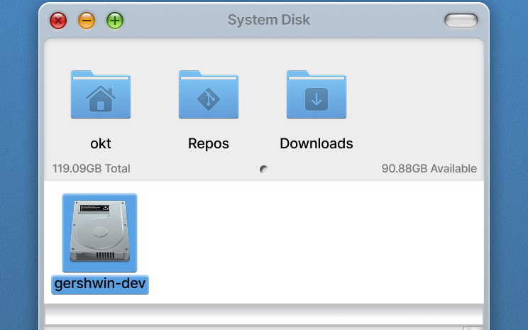 The top of a file browser window titled System Disk: red, amber and green controls in a grey title bar, three blue folders labelled okt, Repos and Downloads, and a selected hard disk icon below them.